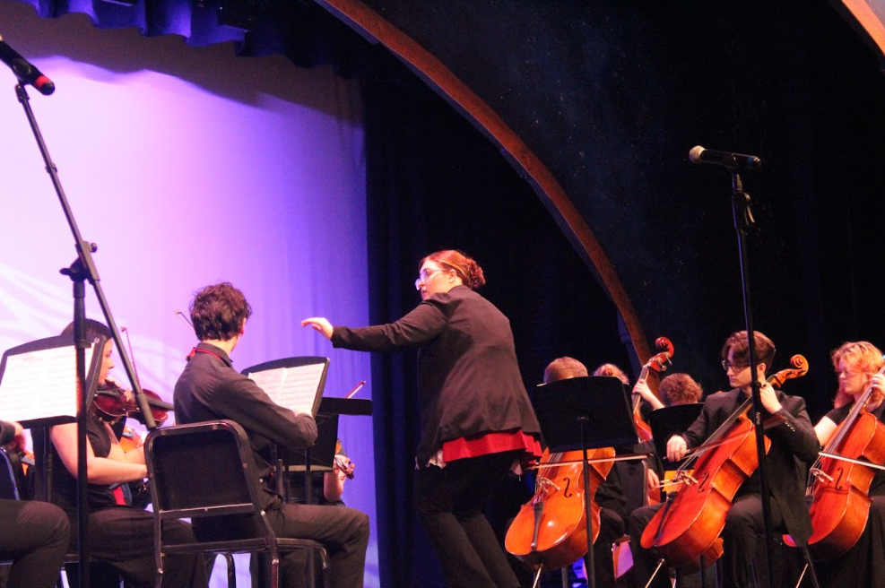 Orchestra teacher, Miss Lane, conducting their performance
